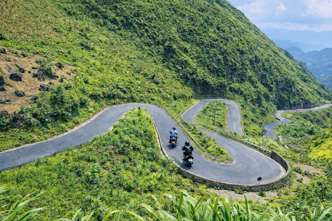 Motorcyclists riding a winding mountain road in Ha Giang Province
